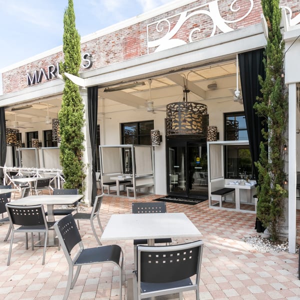 Outdoor patio of Mario's restaurant with tables, chairs, and booth seating under a covered area.