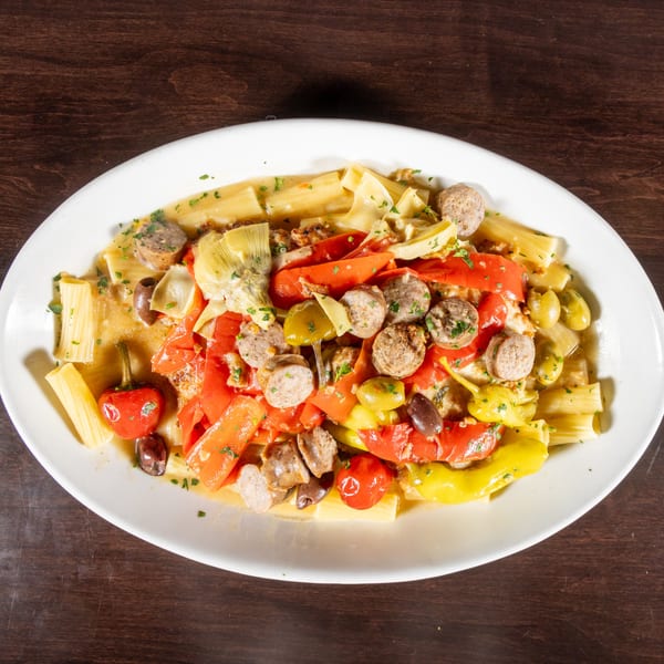 Pasta with sausage, red and yellow peppers, artichoke hearts, and olives in a light sauce.
